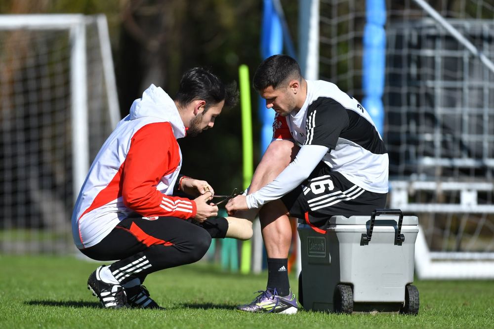 Kinesiólogo atendiendo el pie de un jugador durante el entrenamiento