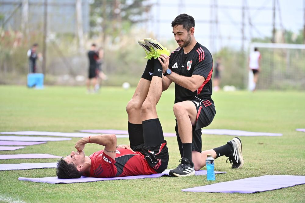 Elongación de pierna sobre una colchoneta en la cancha